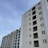 A series of modern multi-story apartment buildings under a clear blue sky. The buildings are tall with multiple windows, and one of the structures appears to be under construction with scaffolding visible.